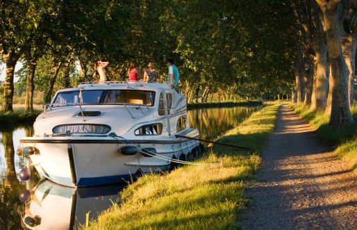 Caprice boat barging down a river under trees